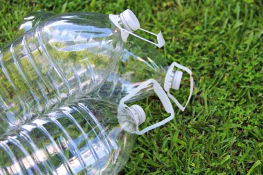 Çöp geri dönüşümü. Çimlerin üzerinde plastik şişeler. Üç boş plastik su şişesi..