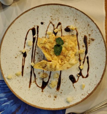 Altın kenarlı beyaz bir tabakta çikolata parçacıklarıyla süslenmiş tatlı..