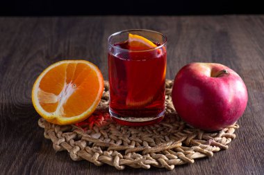 Masanın üzerinde bir bardakta sangria var. Yakınlarda bir elma ve bir portakal var..