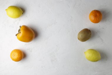 Beyaz arka planda limon, mandalina, hurma ve kivi bulunur. Sağlıklı yiyecek, kopyalama alanı.