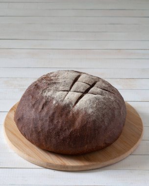 Masanın üzerinde bir somun siyah ekmek var. Beyaz bir arka planda. Boşluğu kopyala.