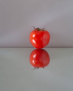 Kırmızı domates ayna masasının üzerinde. Yansımasını görebileceğin bir yere..