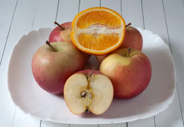 Masada bir tabakta elmalar ve bir portakal var. Bir elma ve bir portakal kesiği..