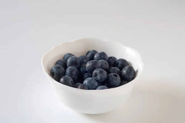 stock image Blueberries are on the table in a white plate. On a white background.