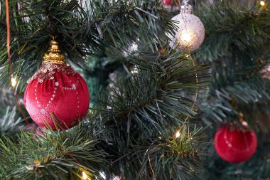 Noel topları ağaçta asılı. Yanlarında çelenk ışıkları yanıyor.