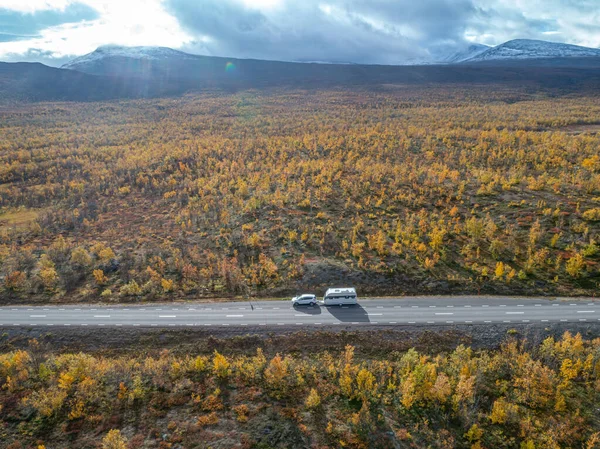 aerial drone footage of Car Camping Caravan driving on road by lake deep in Swedish Lapland. Sunny day and fall colors in Abisko National Park Sweden