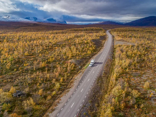aerial drone footage of Car Camping Caravan driving on road by lake deep in Swedish Lapland. Sunny day and fall colors in Abisko National Park Sweden