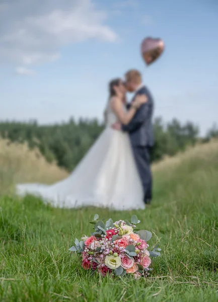 ぼやけたキスのカップルの前で結婚式の花束 花と恋人 — ストック写真