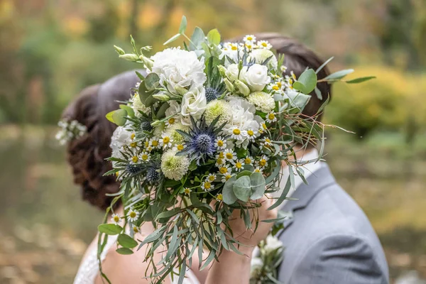 ぼやけたキスのカップルの前で結婚式の花束 花と恋人 — ストック写真