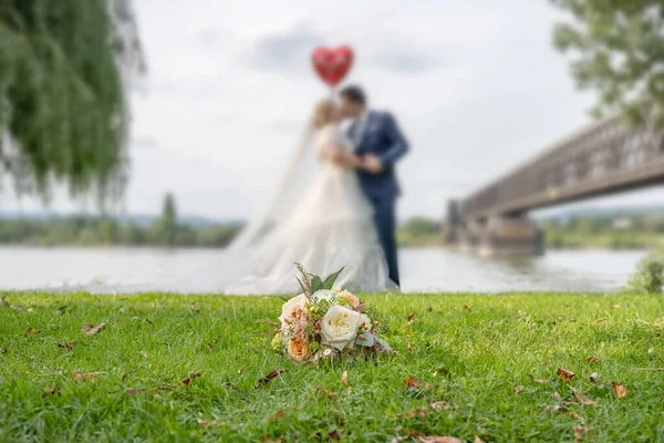 婚礼花束在一对模糊的亲吻夫妇的前景 花和情人 — 图库照片