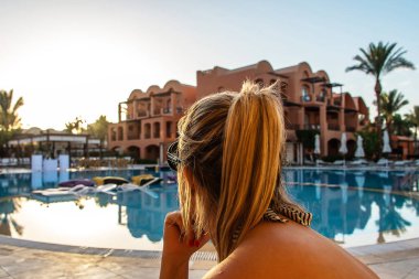 Genç bir kadın, Mısır 'da otel balkonundan gün batımının tadını çıkarıyor. Tropik tatil beldesinde tatil.