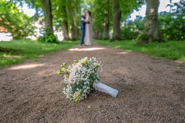 婚礼花束在一对模糊的亲吻夫妇的前景 花和情人 — 图库照片