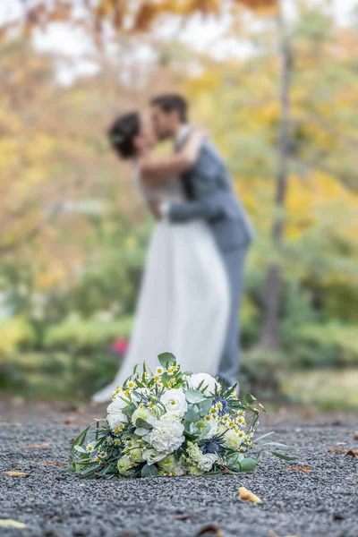Wedding bouquet on foreground of a blurred kissing couple. Flowers and lovers.
