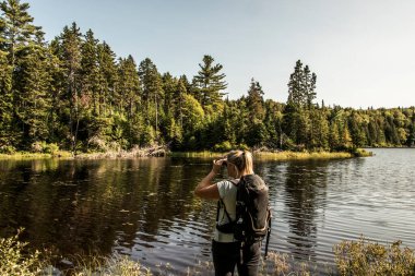 Güzel bir günde La Mauricie Ulusal Parkı Quebec 'te gölün yanındaki ormanda yürüyüş yapan bir kız..