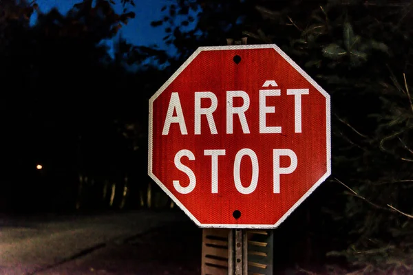 Security stop slow down sign at night in Canada Quebec, arret means stop in french.