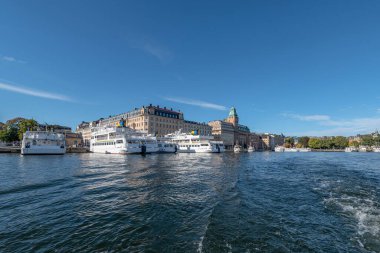 İsveç Stockholm Norrmalm bölgesinin güneşli bir günde taksisi ve teknesi olan manzarası.