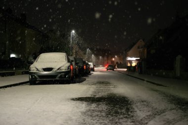 Arka plan bulanık. Şehir manzarası, ışıklar, yağan kar, gece, sokak, hareket halindeki arabaların farları Kış feneri ışığı, kar yağışı