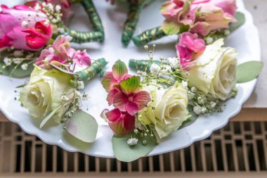 Beyaz mermer tabakta küçük şık yaka çiçekleri, düz, renkli pek çok damat yatıyordu. .