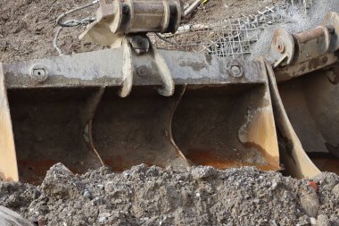 İnşaat alanında toprak kalıntıları ve pas olan ağır kazıcı kovası. Toprak işleri, endüstriyel makineler, inşaat, makineleşme.