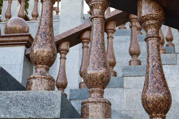 Merdiven üzerinde kırmızımsı kahverengi balyaları olan granit bir balyayı yakından görmek. Klasik mimari ayrıntılar güç ve zarafeti vurguluyor.