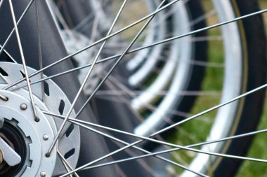 Son derece yakın plan metal bisiklet telleri ve park halindeki bisikletlerin disk frenleri. Simetriyle soyut görünüm ve mekanik detaylara odaklan.