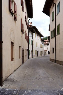 Sessiz bir Avrupa köyünde, renkli panjurları olan eski binalar arasında dar bir kaldırım taşı sokak esiyor. Yumuşak ışık ve boş sokak huzurlu ve zamansız bir atmosferi çağrıştırıyor..