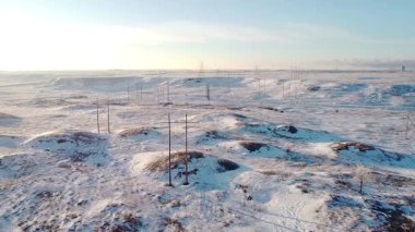 Kışın Kalbinde Karlı Güç Sistemi. Karla kaplı, el değmemiş bir arazinin ortasındaki yayılan güç şebekesinin büyüleyici bir hava görüntüsü..