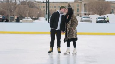 Mutlu genç ve güzel çift, güneşli kışın birlikte buz pistinde burunlarına dokunarak vakit geçirirler. Yüksek kalite 4k görüntü