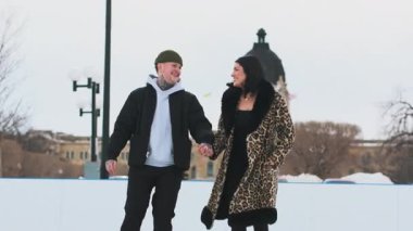 Karla kaplı bir sokakta kayan ve el ele tutuşan bir çift. Yüksek kalite 4k görüntü