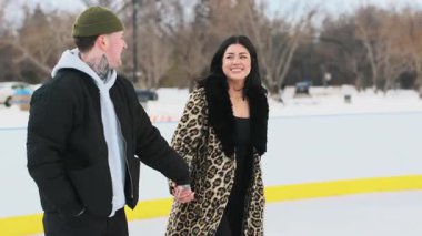 Karla kaplı bir sokakta kayan ve el ele tutuşan bir çift. Yüksek kalite 4k görüntü