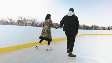 Çift güneşli bir günde açık bir gölde güzel bir manzarayla paten kayıyor. Erkek ve kadının kış gölünde randevusu var. Yüksek kalite 4K görüntü. Yüksek kalite 4k görüntü