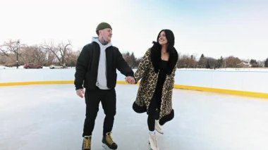 Çift güneşli bir günde açık bir gölde güzel bir manzarayla paten kayıyor. Erkek ve kadının kış gölünde randevusu var. Yüksek kalite 4K görüntü. Yüksek kalite 4k görüntü