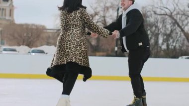 Karla kaplı bir sokakta kayan ve el ele tutuşan bir çift. Yüksek kalite 4k görüntü