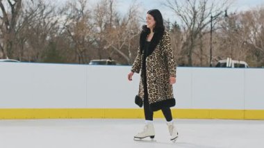 Mutlu aşıklar buz pateni pistinde birbirlerine doğru kayıyor ve kucaklaşarak dönüyorlar. Sevgili çift soğuk kış gününde eğleniyor. Yüksek kalite 4k görüntü