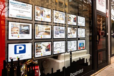 Barselona, İspanya-19 Mart 2025. Emlak acentesinin vitrininde mülk listeleri ve kat planları var..