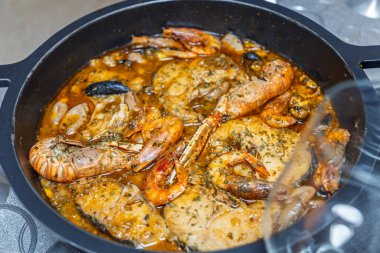 Suquet de peix. Maymun balığı, karides, Norveç ıstakozu ve midyeyle birlikte siyah bir tavada kaynayan geleneksel bir İspanyol balık güveci.