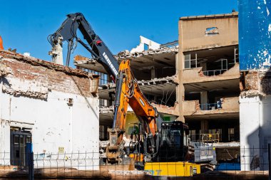 Badalona, İspanya-09 Mart 2025. Kazıcıların açık mavi gökyüzü altındaki bir binayı yıktığı bir yıkım alanı.