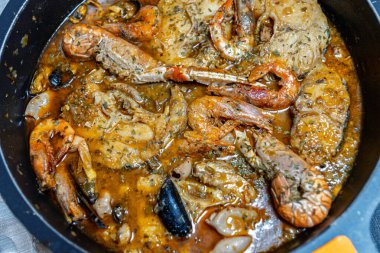 Karides, yengeç ve çeşitli kabuklu deniz hayvanlarının bol baharatlı sosla süslendiği deniz ürünleri tabağının yakından görüntüsü..