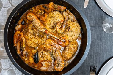 Suquet de peix. Maymun balığı, karides, Norveç ıstakozu ve midyeyle birlikte siyah bir tavada kaynayan geleneksel bir İspanyol balık güveci.