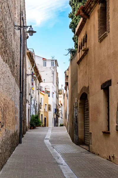 İspanya 'nın Badalona kentindeki tarihi Dalt de la Vila mahallesinde eski Akdeniz tarzı binalar ve mavi gökyüzü bulunan büyüleyici dar bir cadde..