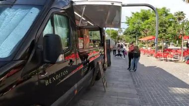 Badalona, İspanya-4 Şubat 2025. Güneşli bir yaz gününde sokak yemekleri satan bir şehir panayırında yemek servisi sunan küçük bir yemek kamyonu işi.