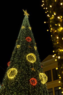 Aydınlatılmış Noel ağacı ve süslemesi olan şenlikli bir mimari. Badalona, İspanya