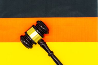 Arka planda Alman bayrağı renkleri olan bir yargıcın tokmağı yüzeyde dinleniyor..