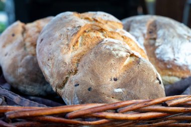 Üç somun ekmek bir sepette duruyor. Ekmek kabuklu ve hafif yanmış bir kokusu var. Sepet bir masanın üzerinde, ve ekmek onu iştah açıcı gösterecek şekilde düzenlenmiş.