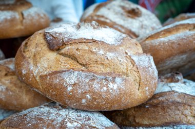 Üstünde bir sürü beyaz un olan bir yığın ekmek. Ekmek kahverengi ve kabuğu var.