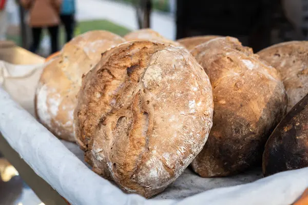Altında beyaz bir bez olan bir sepet ekmek. Ekmek kahverengi ve kabuğu var.