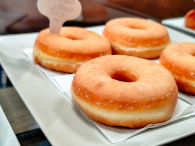 Beyaz bir tabakta jöleli çörekleri yakın plan, arka planda küçük bir tabela ile düzenlenmiş..