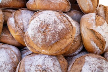 Üstünde bir sürü beyaz un olan bir yığın ekmek. Ekmek kahverengi ve kabuğu var.