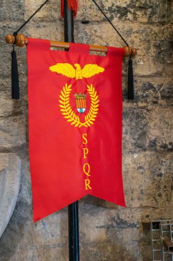 Dikey görünümlü kırmızı pankart, antik Roma 'nın sembolü, bir kartal, defne çelengi ve efsanevi SPQR' dan oluşuyor. Senatus Populus que Roman