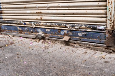 Kapalı metal bir kepenkte aşınma ve kırık boya izleri var. Kriz konsepti, ana cadde dükkanlarındaki satışların azaltılması.